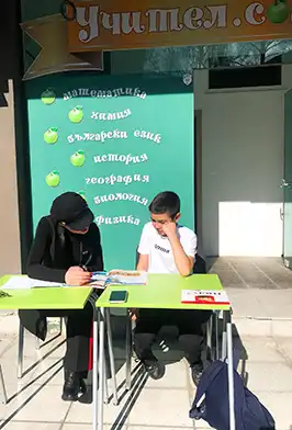 Ученици учат пред школата на Учител.com с табло с предмети